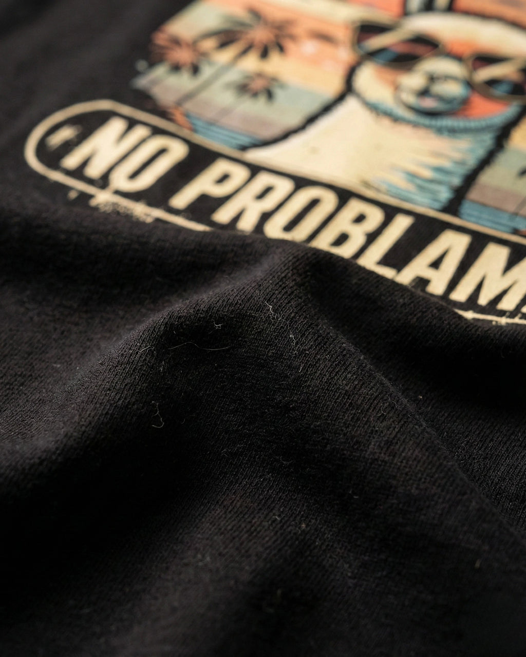 Detailaufnahme des "No Problama" Lama-Drucks auf dem T-Shirt in Schwarz.