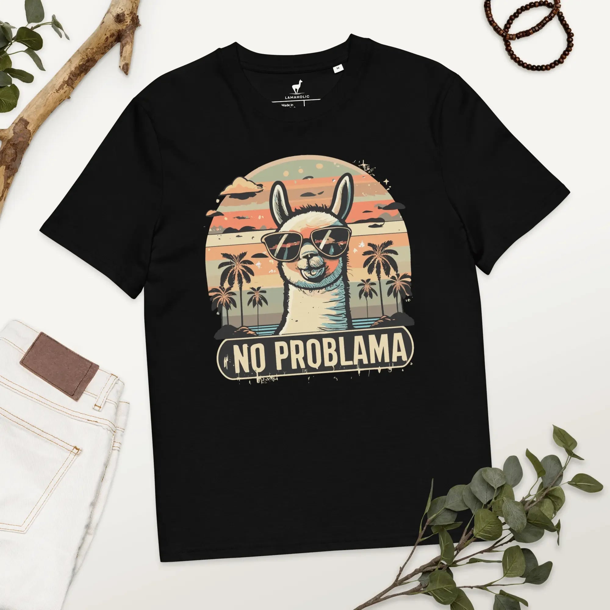 Lustiges Lama T-Shirt in Schwarz mit "No Problama" Design, flach liegend auf einem Holztisch.